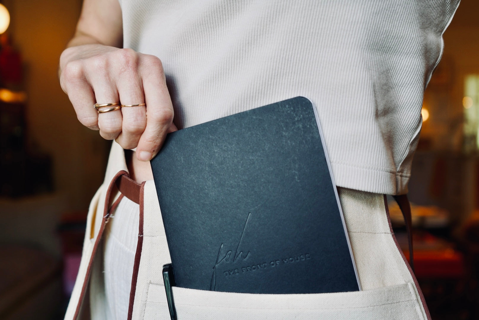 Person holding a dark blue leather-bound notebook with visible branding.
