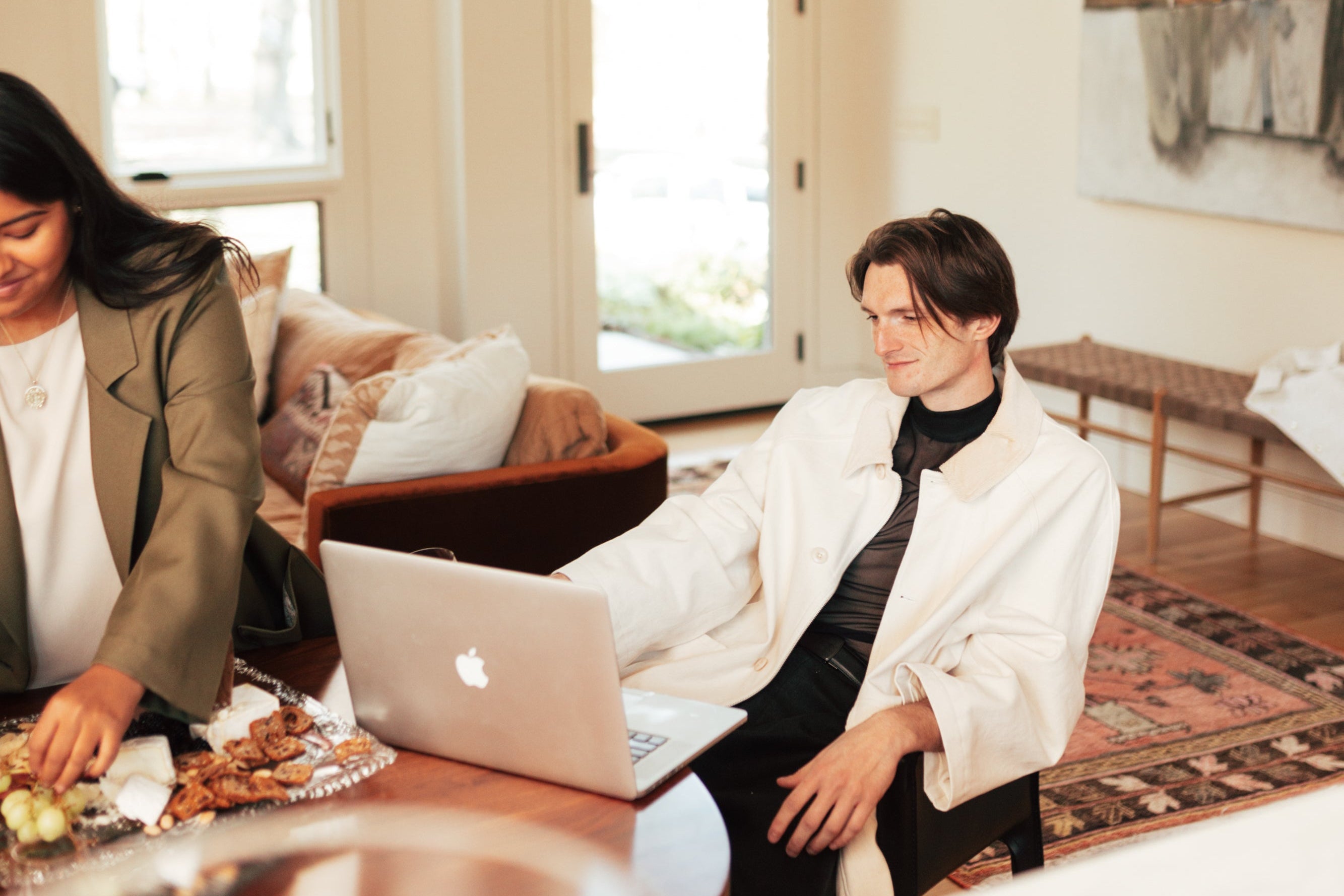 Two people sitting at a table with a laptop in a living room.